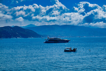 Fisherman boat and large yacht in Portofino Liguria Italy