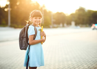 Happy little schoolgirl with a backpack on her way to school.