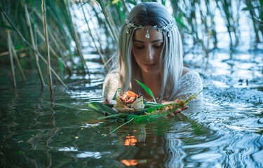 Mermaid girl bride in white dress in lake. Fantasy girl. Mysterious scene. Witch standing in the river and practice witchcraft. Fairytale