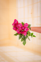 Women hand holding a bouquet of Moody Blues roses variety, studio shot.