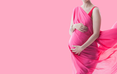 pregnant woman holding her belly on pink background 