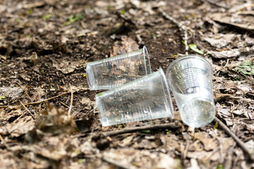 Obraz premium Plastic cups scattered on the ground in the forest