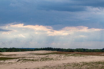 Desert in spring distant view on sand dunes near forest with epic dark sky. Kitsevka desert hilly sands in Ukraine, Kharkiv region landscape
