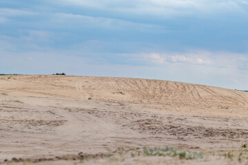 Desert in spring distant view on sand dunes near forest with epic dark sky. Kitsevka desert hilly sands in Ukraine, Kharkiv region landscape