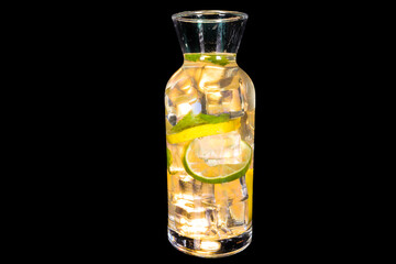 Fresh lemonade with Elderflower syrup in a bottle with lemon and ice with reflection, isolated on black background