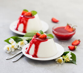 Cream dessert panna cotta vanilla with strawberry sauce on a light gray background
