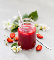 Strawberry sauce in a jar on a light gray background