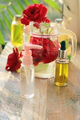 Fresh roses, spray and bottles with aromatic oil on a wooden windowsill, natural homemade cosmetics, healthy lifestyle