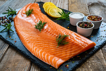 Fresh raw salmon fillet on black stone board
