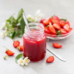 Strawberry sauce in a jar on a light background