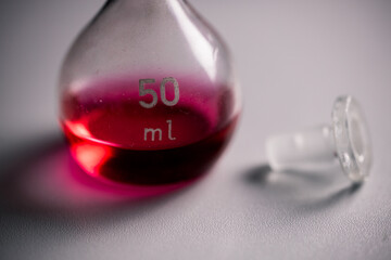closeup of two conical erlenmeyer flasks with red liquid and a glass plug.