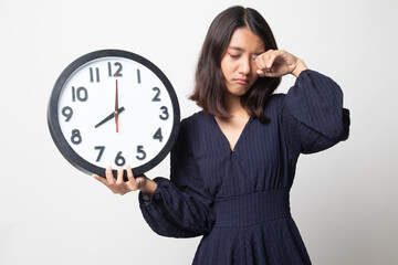 Sleepy young Asian woman with a clock in the morning.