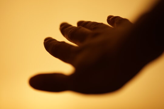 dark human hand is flying in a warm yellow space