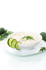 summer cucumber soup with vegetables in a plate on white background