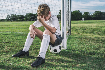 Young Soccer Player Sitting on Soccer Ball At Soccer Field