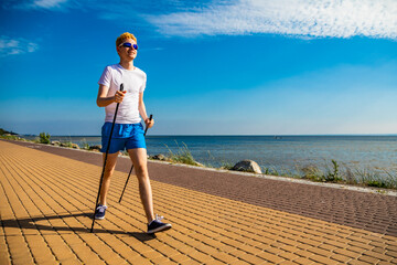 Nordic walking - young man training by the sea shore