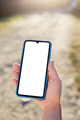 Girl holds a mobile phone on vacation in nature. Mockup