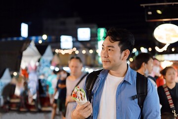 A man walking in night market.