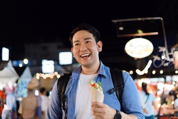 A man walking in night market.