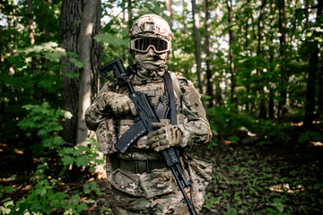 Obraz premium Portrait of a military soldier with a weapon in his hands in the forest thicket