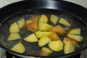 raw fresh new yellow potato being cooked in the saucepan with boiling water