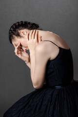 The young female bows her head and holds her face and neck. The concept of diseases of the neck and spine.