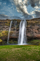 Obraz premium Seljalandsfoss - Seljalandsfoss is located in the southern region of Iceland, just off Highway 1. One of the cool things about this waterfall is that visitors can walk behind it into a small cave.