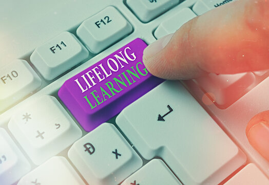 Text sign showing Lifelong Learning. Business photo text pursuit of knowledge for an individualal or professional reasons White pc keyboard with empty note paper above white key copy space
