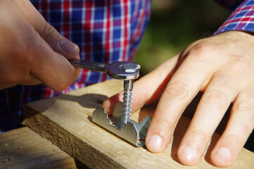A carpenter with a wrench in hand tightens the screw