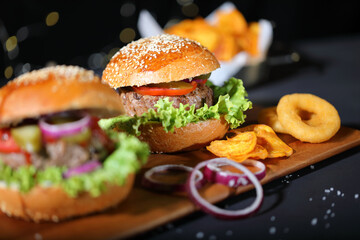 Big hamburger with salad, french fries, onion rings and cheese.