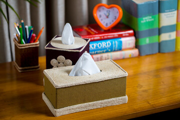 A tissue box on a wooden reading table. A tissue box made of fiber. Pineapple leaf fiber.