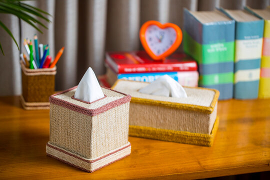A tissue box on a wooden reading table. A tissue box made of fiber. Pineapple leaf fiber.