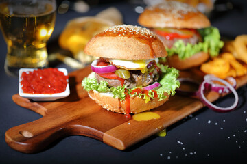 Big hamburger with salad, french fries, onion rings and egg.