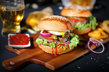 Big hamburger with salad, french fries, onion rings and egg.
