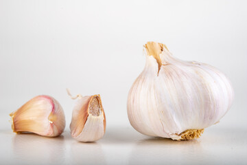A whole head of garlic and a few cloves of garlic. Vegetables used in home cooking.