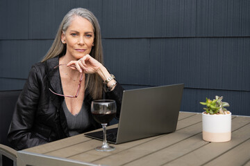 Beautiful mature woman working outside on a laptop