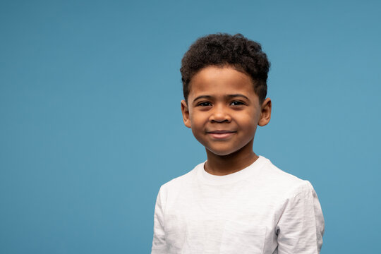 Happy little boy of African ethnicity in t-shirt standing in front of camera