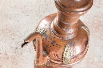 Antique copper jug with lid on concret background.