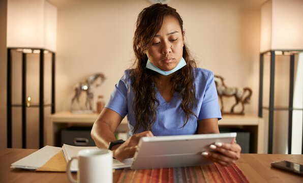 Filipina Nurse Working From Home Doing Paperwork And Using Tablet