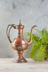 Antique copper jug with lid on concret background.