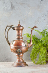 Antique copper jug with lid on concret background.