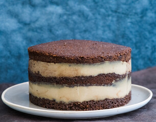 Chocolate cake with vanilla cream on a blue background. Ready for further decoration. Copy space.