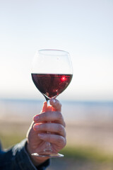 against the background of the sea a glass with wine in hand