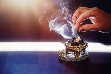 incense in a woman hand, incense smoke on a black background.