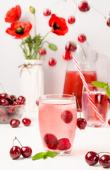 Summer cooling drink with cherries and blurry flying berries in the background.