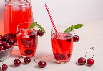 Summer cooling drink with cherries, ice and mint on a white background with copy space.