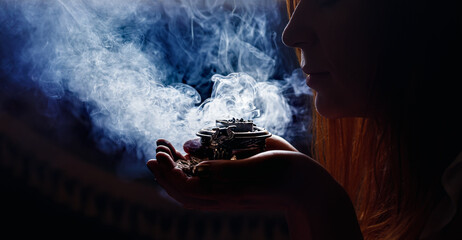 incense in a woman hand, incense smoke on a black background.