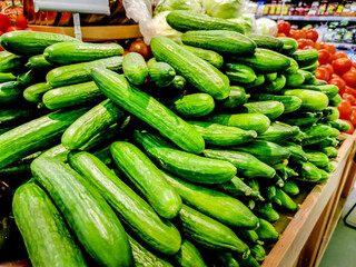green fresh cucumbers are piled up in a store for sale