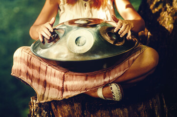 beautiful woman playing with hangdrum in nature.