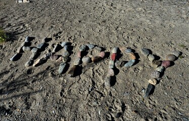 Scripture Happy with different colored stones in the sand